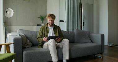 A man sitting on a couch with a tablet computer video