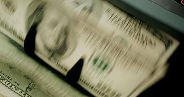 A stack of money is being counted by an atm machine video