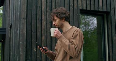 A man is standing outside holding a cup of coffee video