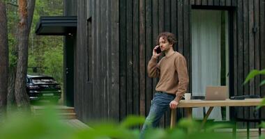 A man talking on a cell phone in front of a wooden house video