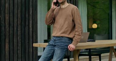 A man in a brown sweater talking on a cell phone video