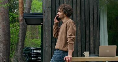 A man is standing on a wooden table talking on his cell phone video