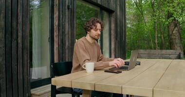 A man sitting at a table with a laptop and coffee video