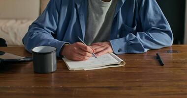 A man is sitting at a table with a notebook and pen video