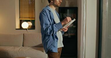 A man is standing in front of a window with a tablet video