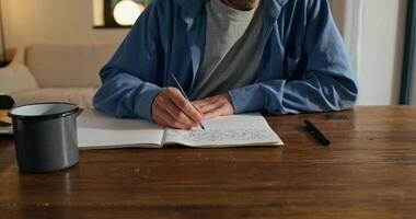 A man is writing on a notebook while sitting at a table video