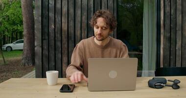A man sitting at a table with a laptop and a cup of coffee video