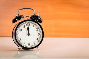 Black alarm clock on the table. Twelve o'clock photo