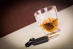 Glass with cognac or whiskey and car keys on table photo