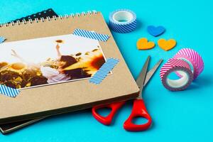 Creative scrapbook setup with photo of sunflower field and colorful crafting materials on a bright blue background
