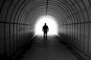 Man walking towards light at end of tunnel photo