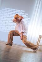 Young dancer performs dynamic move in bright studio space during daytime practice session photo