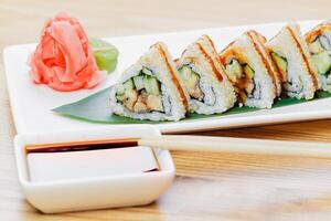 Delicious sushi rolls served on a plate with ginger and soy sauce in a cozy dining setting photo