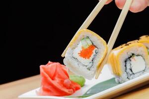 Delicious sushi roll being picked up with chopsticks in a restaurant setting photo
