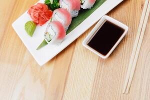 Slices of fresh sushi neatly arranged on a wooden table with soy sauce and garnishes photo