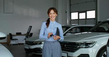A woman in a business suit standing in front of a car video