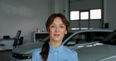 A woman in a car dealership stands in front of a car video