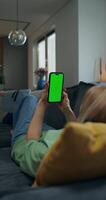 Woman using smartphone with green screen at home video