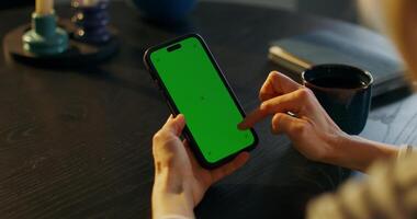 Woman using smartphone with green screen at home video