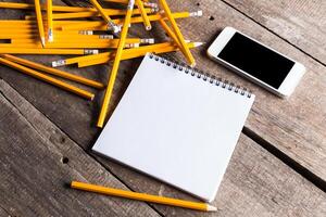 Creativeness concept with plenty of pencils and open blank notebook photo