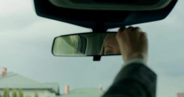 A person is looking at the rear view mirror of a car video