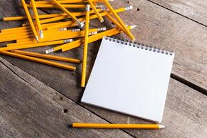 Creativeness concept with plenty of pencils and open blank notebook photo