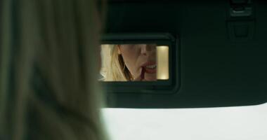 A woman is looking at a camera in the rear view mirror video
