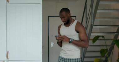 A man in a tank top is looking at his phone video