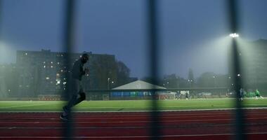 A man running on a track in front of a fence video