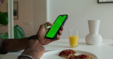 Man using smartphone with green screen at breakfast table video