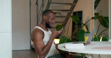 A man sitting at a table with a laptop and cell phone video