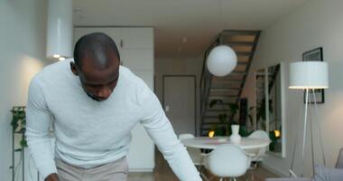 A man is standing in a living room with a laptop video