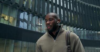 A man in a sweater is standing in front of a building video