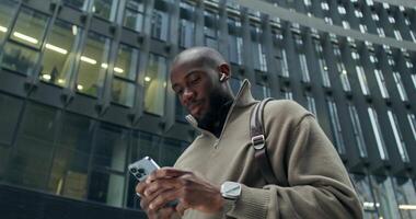A man in a sweater is looking at his phone video