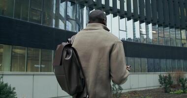 A man with a backpack walking in front of a building video