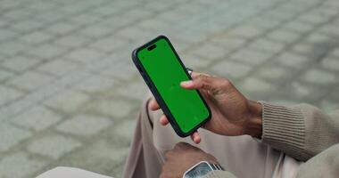 A man is holding a green screen on his phone video