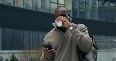 A man is holding a cup and looking at his phone video