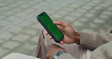 A man holding a smart phone with a green screen video