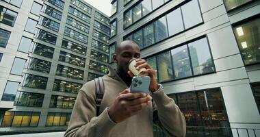 A man holding a cell phone and drinking coffee video