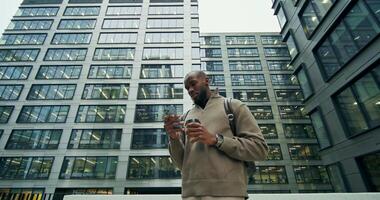 A man standing in front of a building with his cell phone video