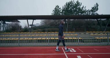 A man is walking on a track in front of a stadium video