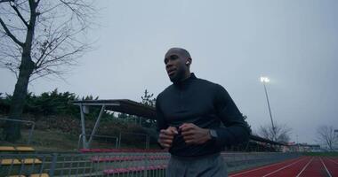 A man running on a track in front of a stadium video