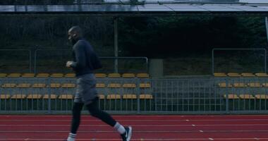 une homme fonctionnement sur une Piste avec une stade dans le Contexte video