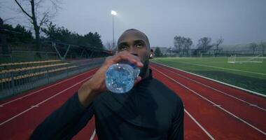 A man drinking water on a running track video