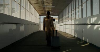 A woman with a suitcase walks down an empty hallway video