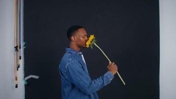 A man holding a sunflower in front of a blackboard video