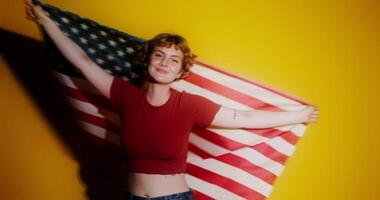 A woman holding an american flag in front of a yellow background video