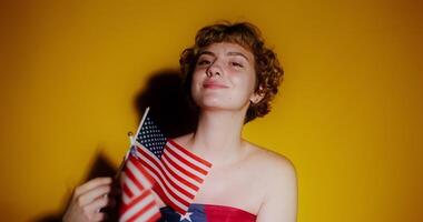 A woman holding an american flag in front of a yellow background video
