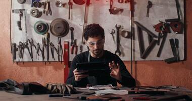 A man is working on a tablet in a workshop video