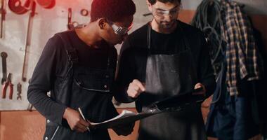 Two men in work clothes looking at a piece of paper video